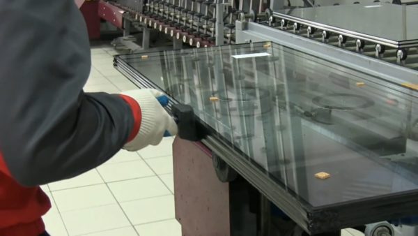 Сборка стеклопакета. Чтобы обеспечить адгезию герметика, мягкое энергосберегающее напыление приходится зачищать вдоль всей кромки.